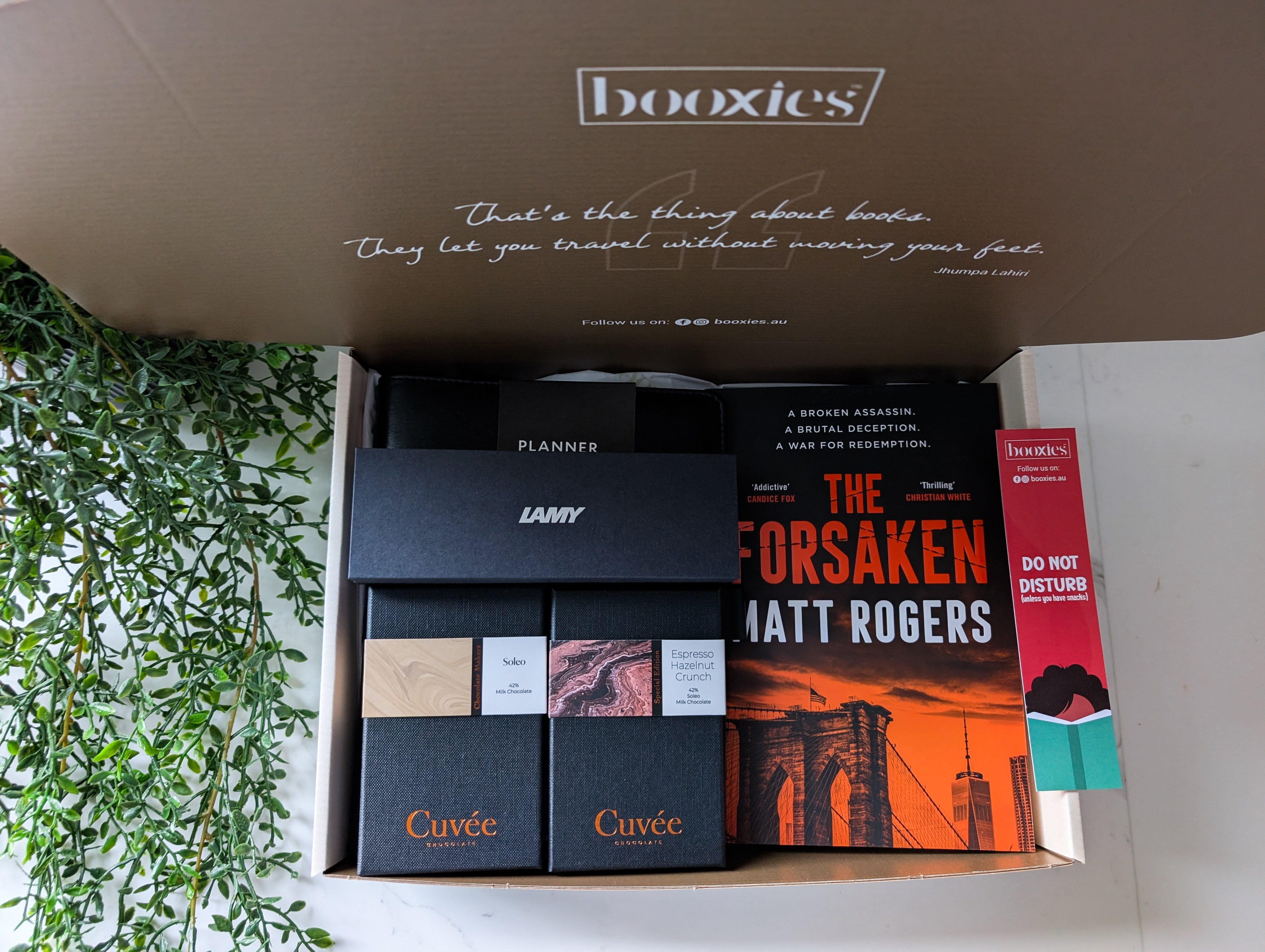 Open box containing books with 'booxies' branding and a plant on the side.
