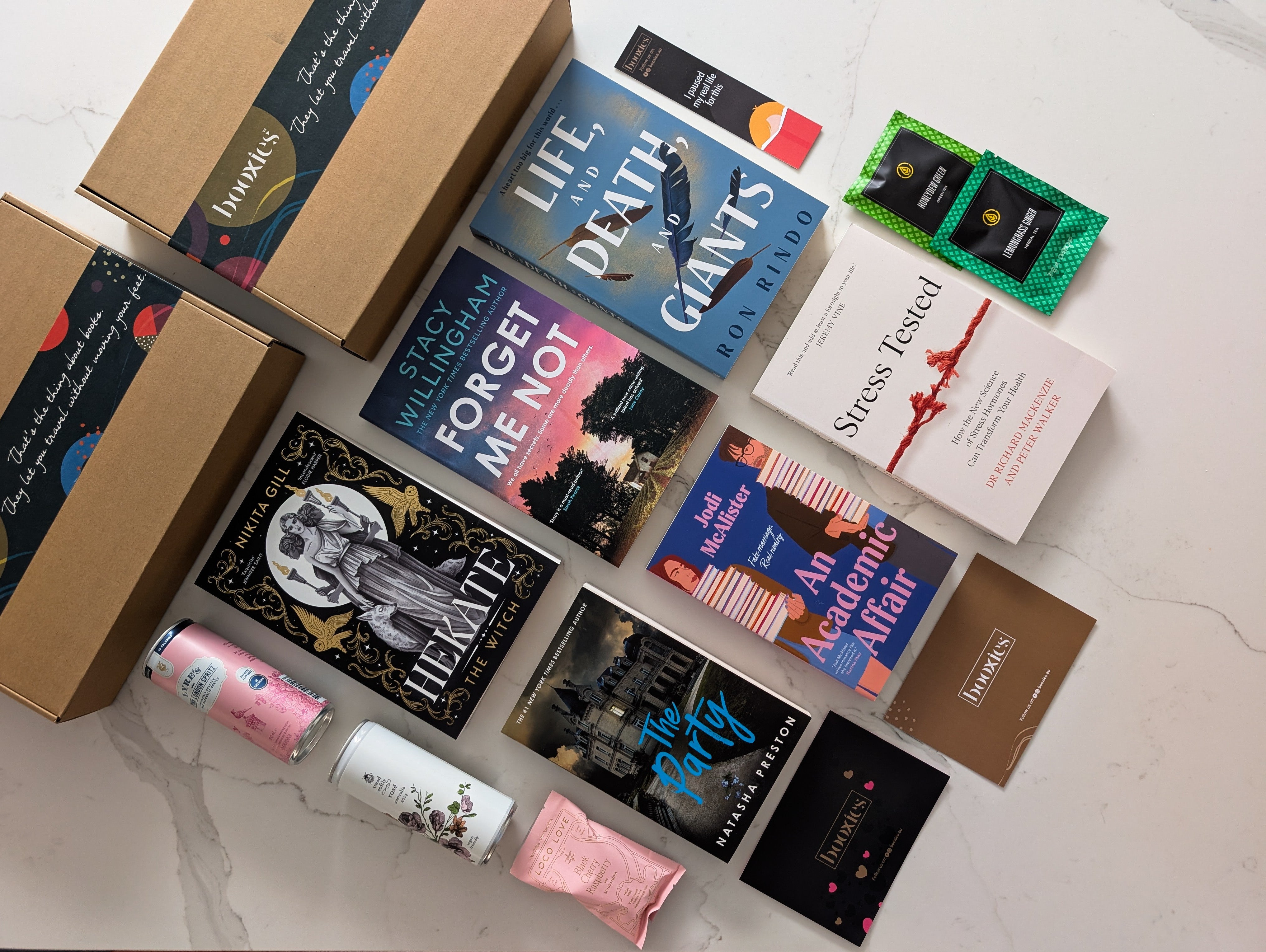 Collection of books and snacks on a marble surface representing October Mystery Booxies