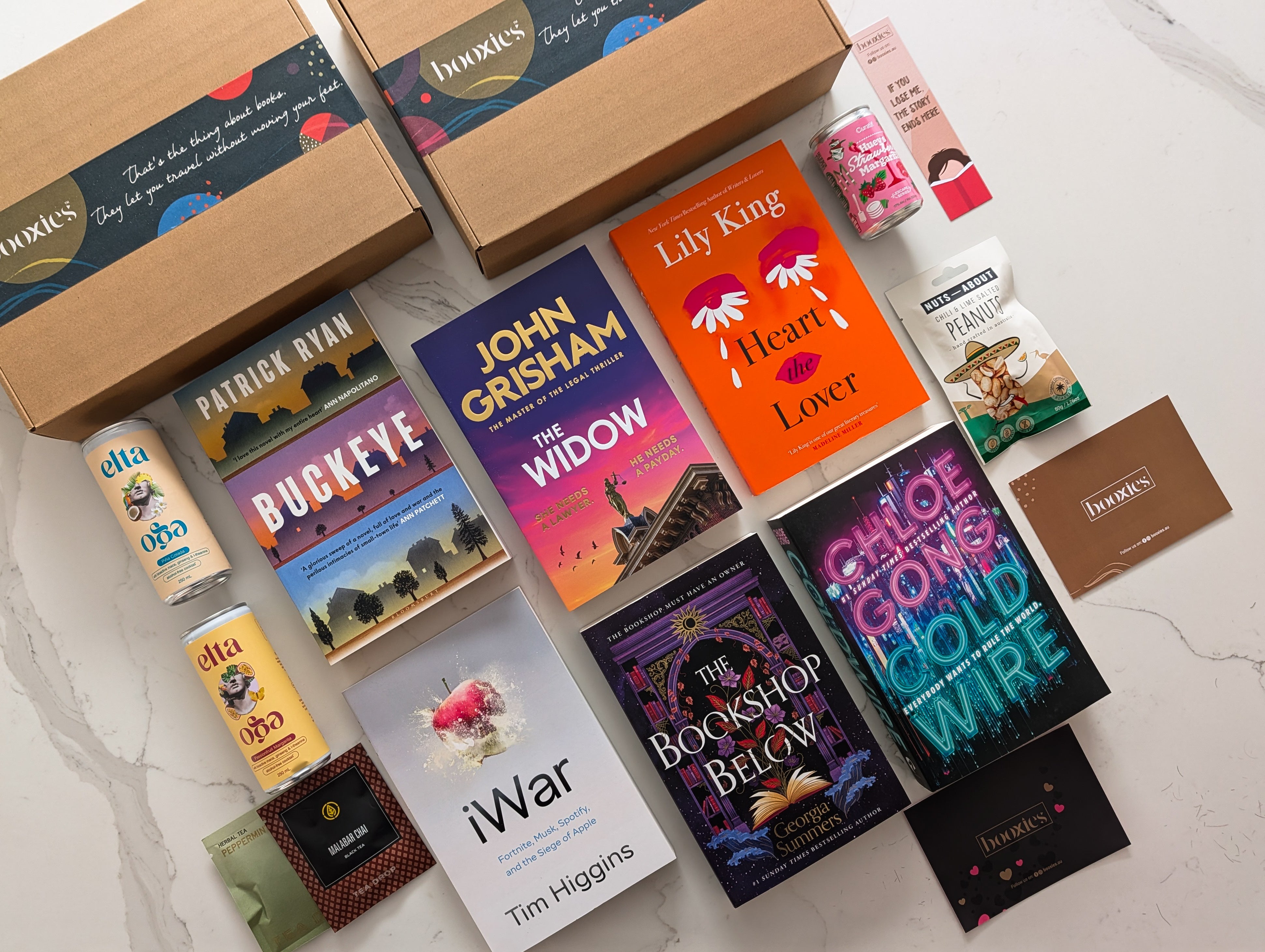 Collection of books and snacks on a marble surface with a box labeled 'booqies'. for January 2026 Mystery Booxies