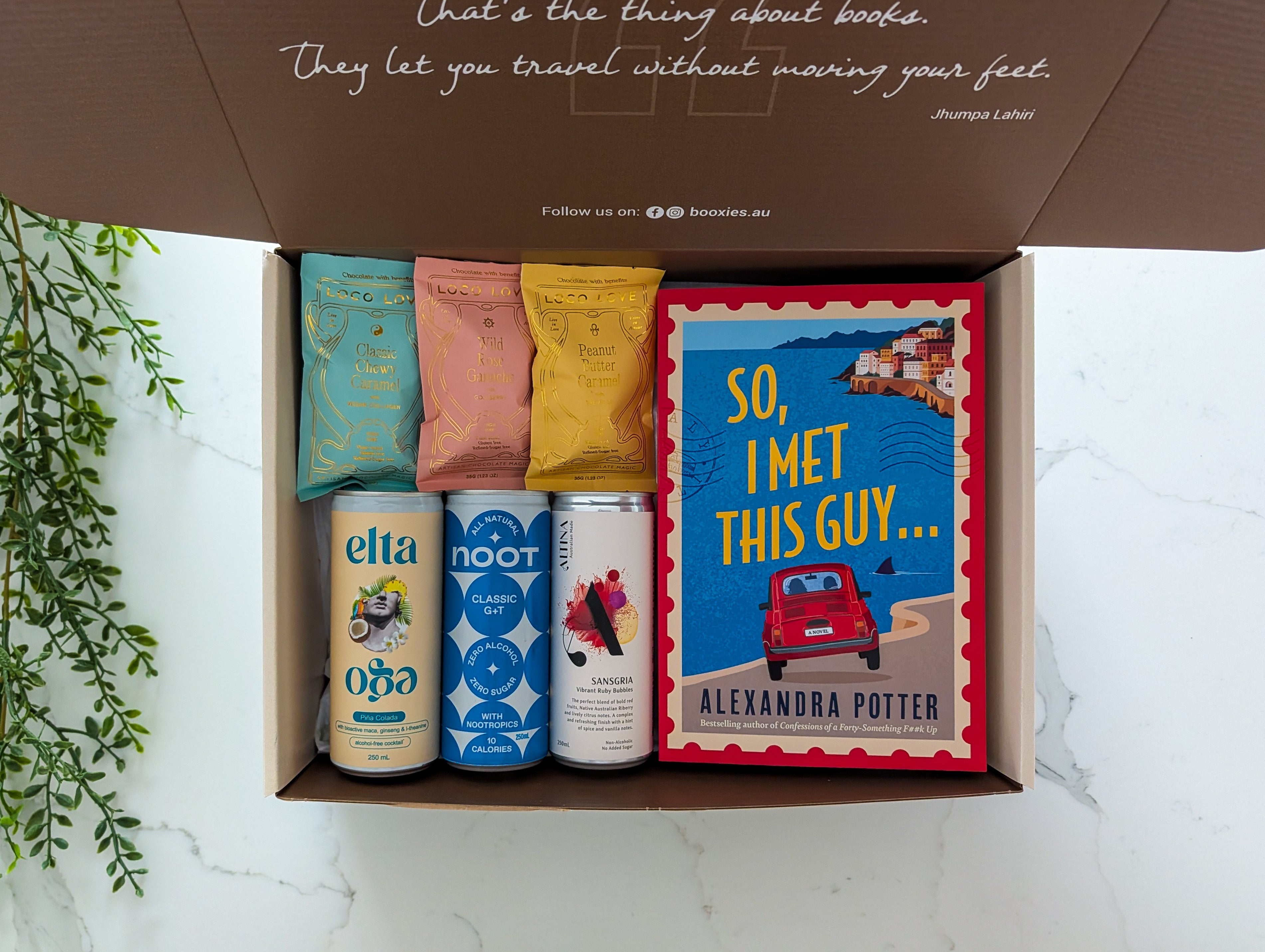 Open box containing a book titled 'So, I Met This Guy' by Alexandra Potter, along with snacks and drinks.
