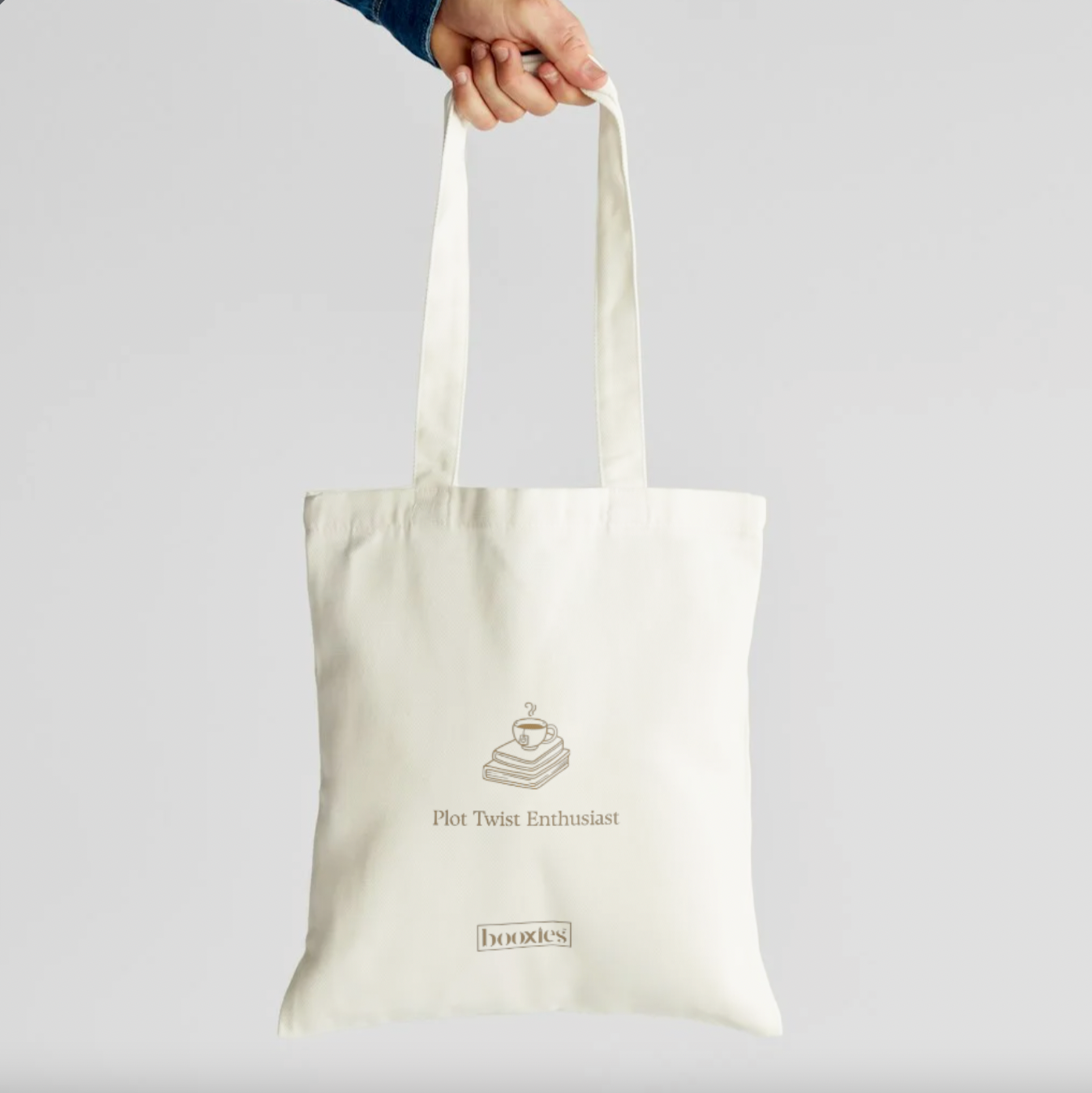 Organic cotton book lover tote bag showing a cozy illustration of coffee and novels with the text Plot Twist Enthusiast.