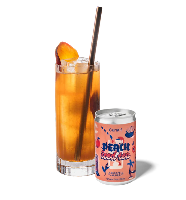 Glass of peach iced tea with a can of Curatif Peach iced tea on a white background