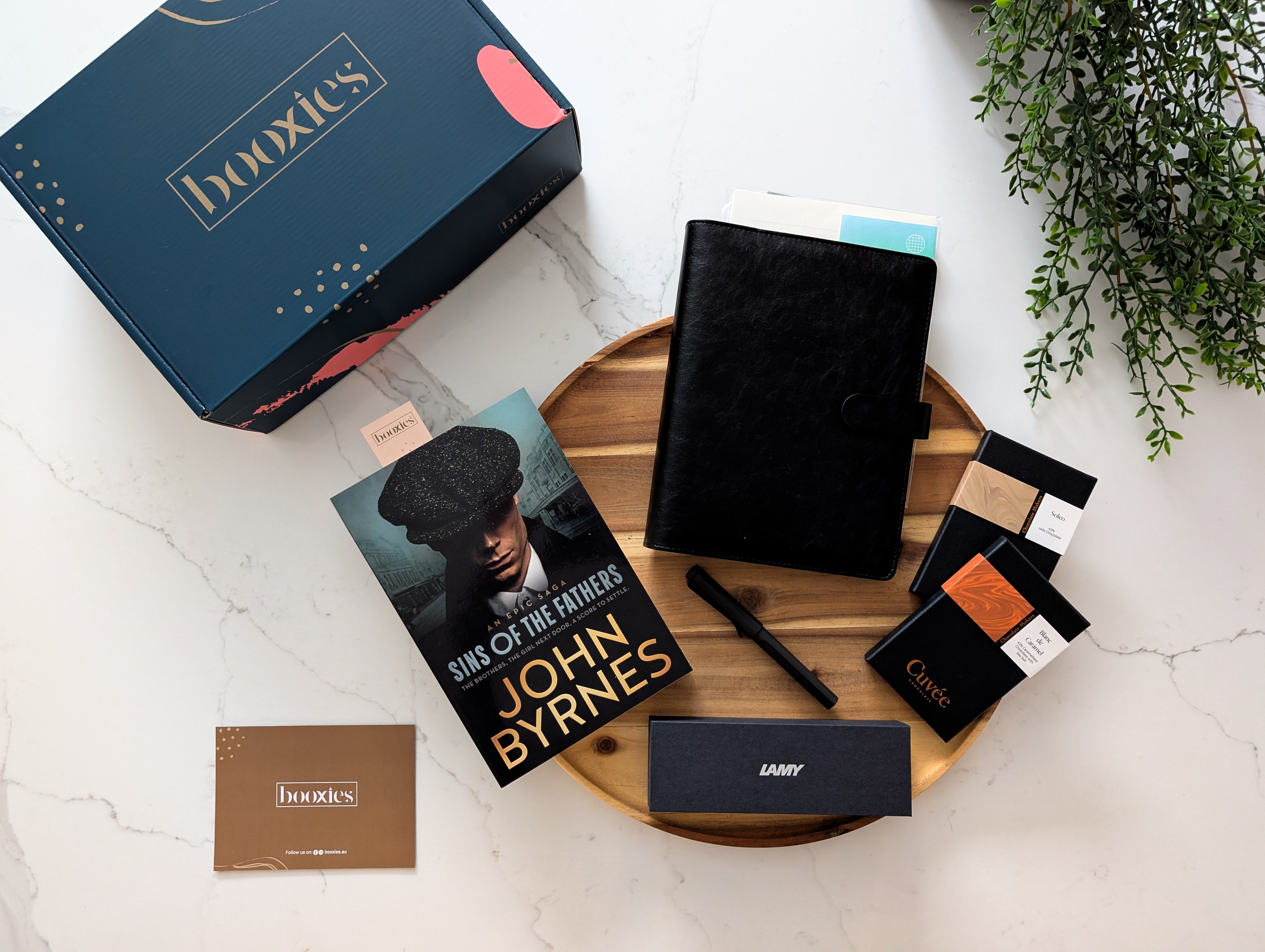 Booxies product packaging with a book and stationery items on a wooden tray.
