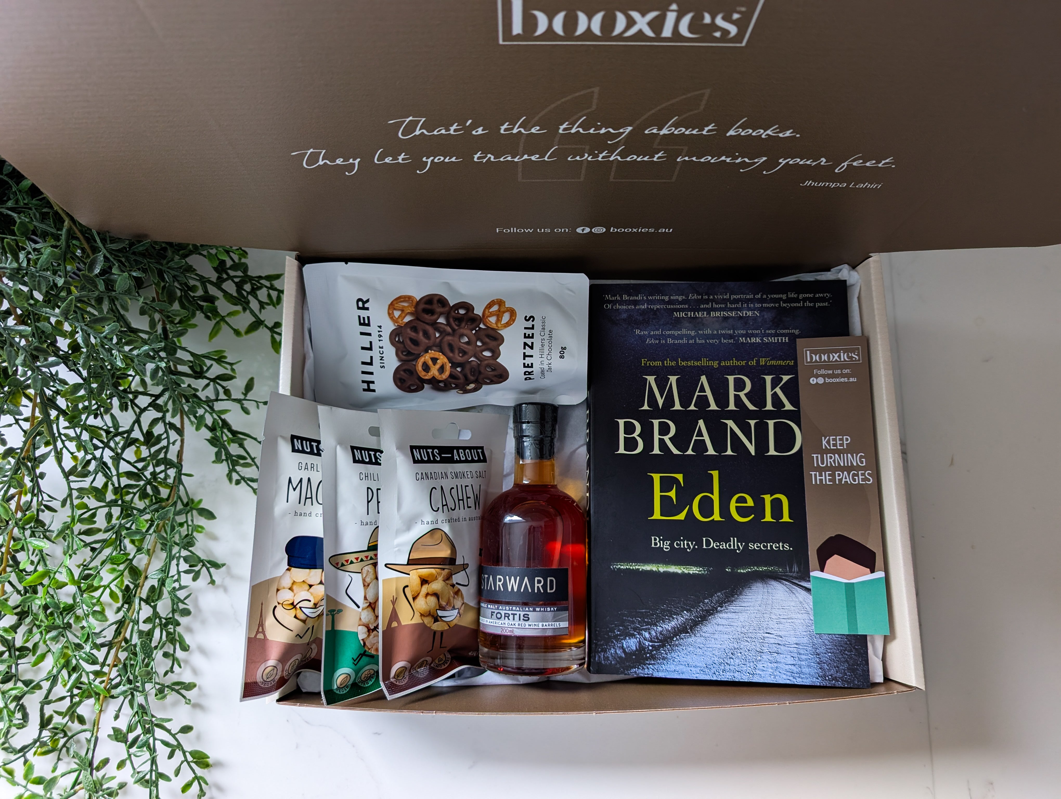 Book and snack subscription box with 'booxies' branding, featuring a book titled 'Eden' and snacks.