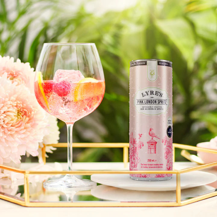 Lyre's Pink London Spritz can with a glass of pink cocktail on a decorative tray outdoors.