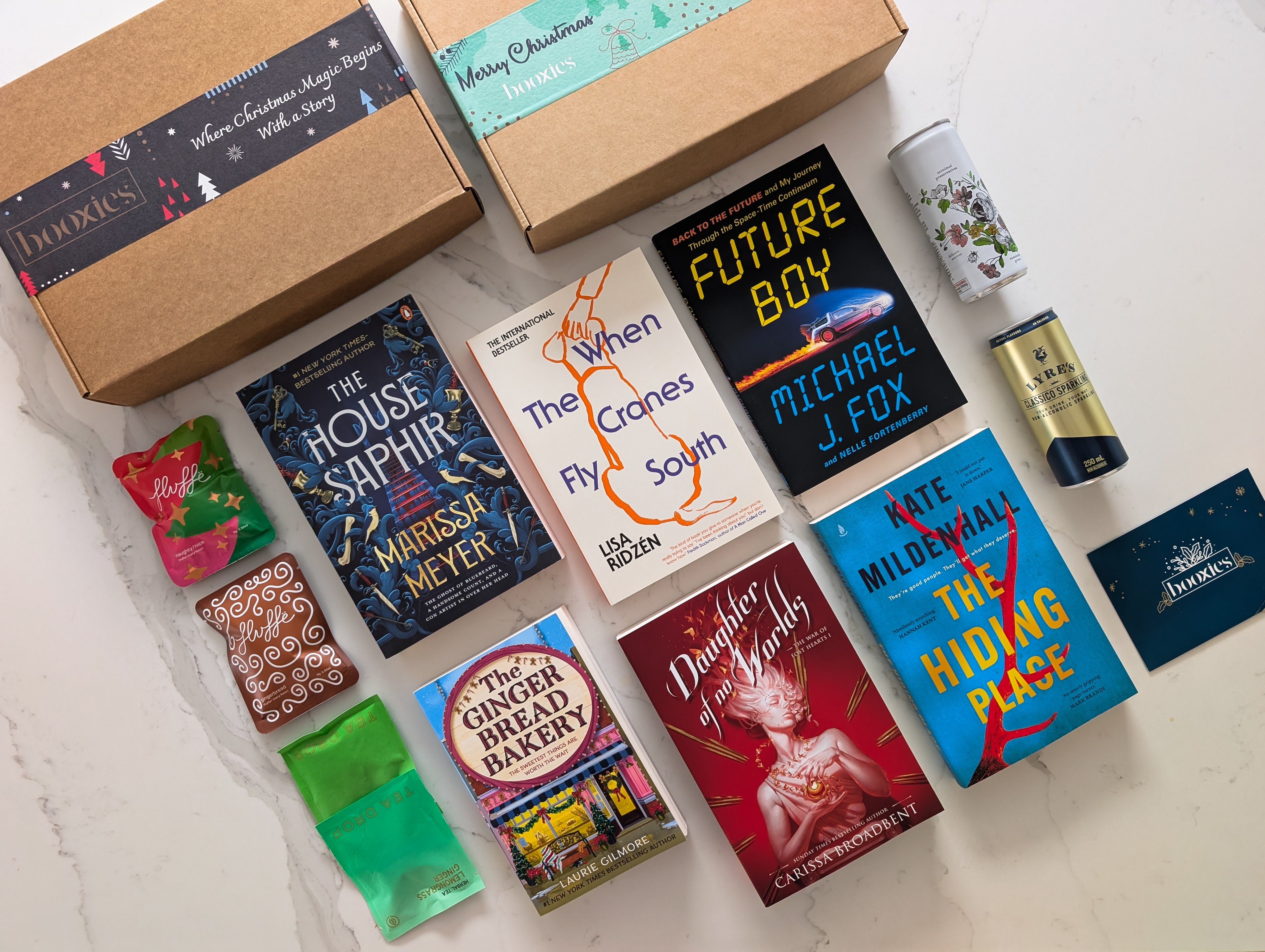 Collection of books and snacks on a white surface with a cardboard box labeled 'Hedonist'.