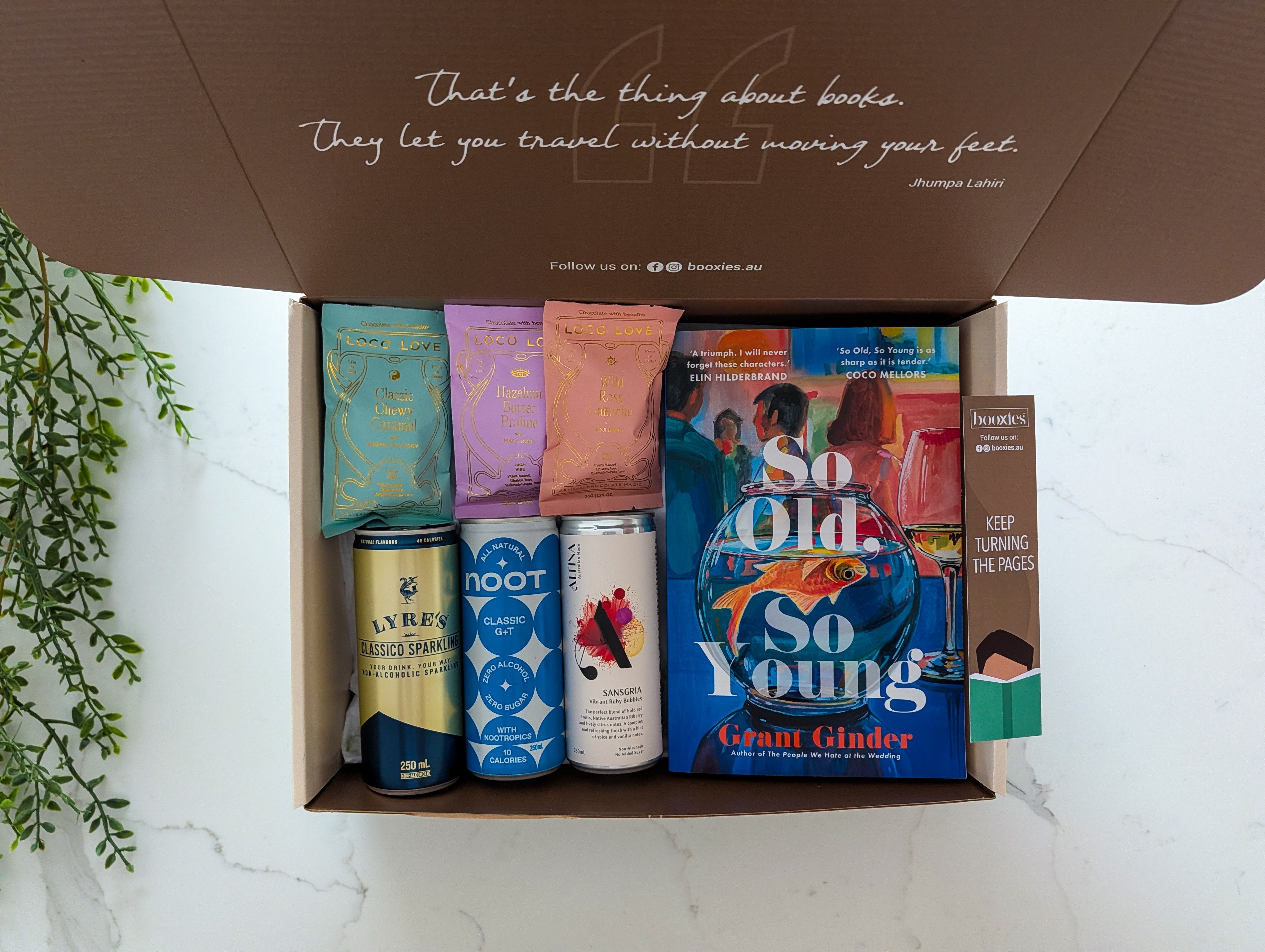 Open box containing books and drinks with a quote on the lid.