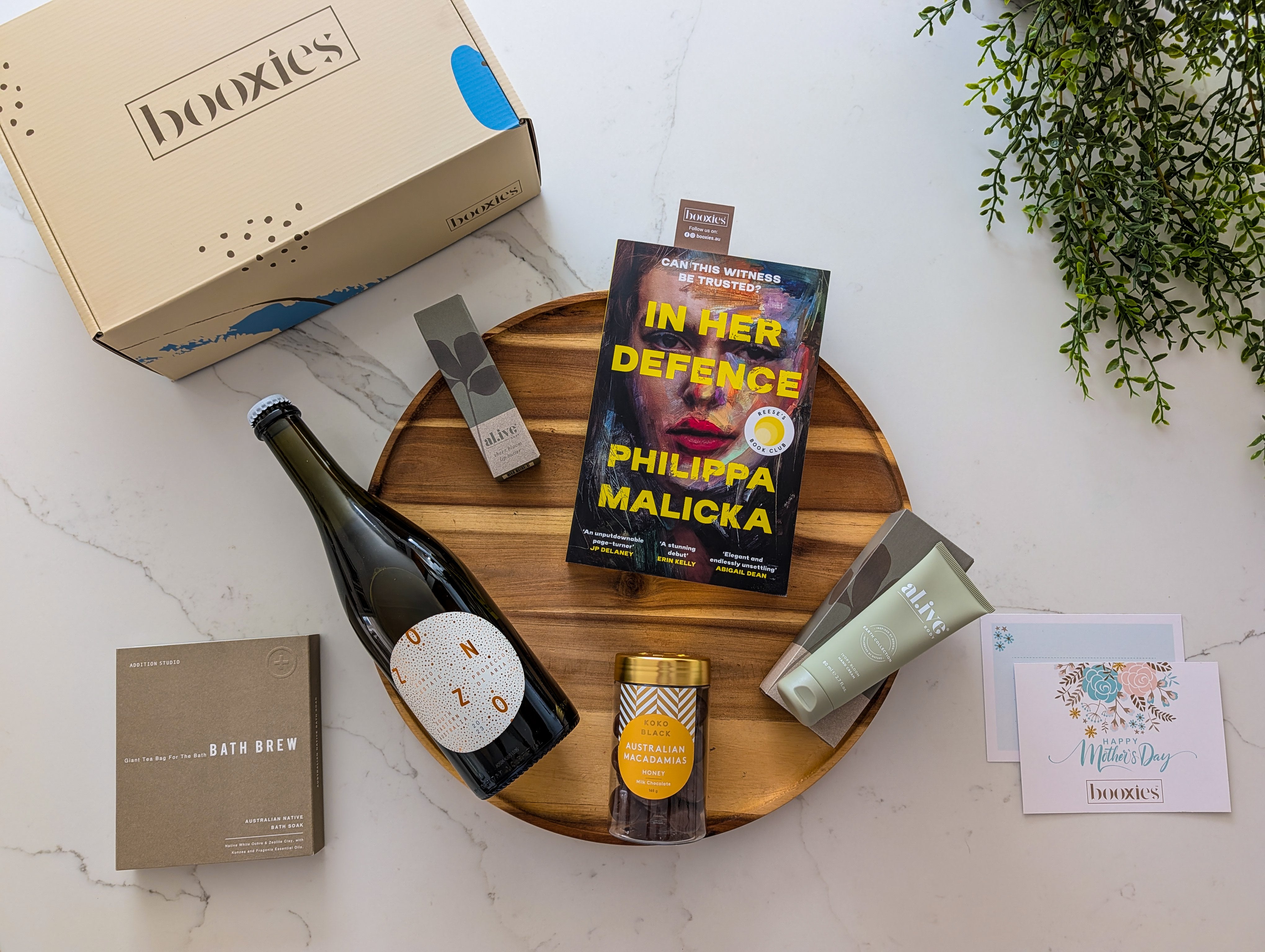 Booxies box with a book, bottle of Zonzo prosecco, and other items on a marble surface making Mother's day gift box