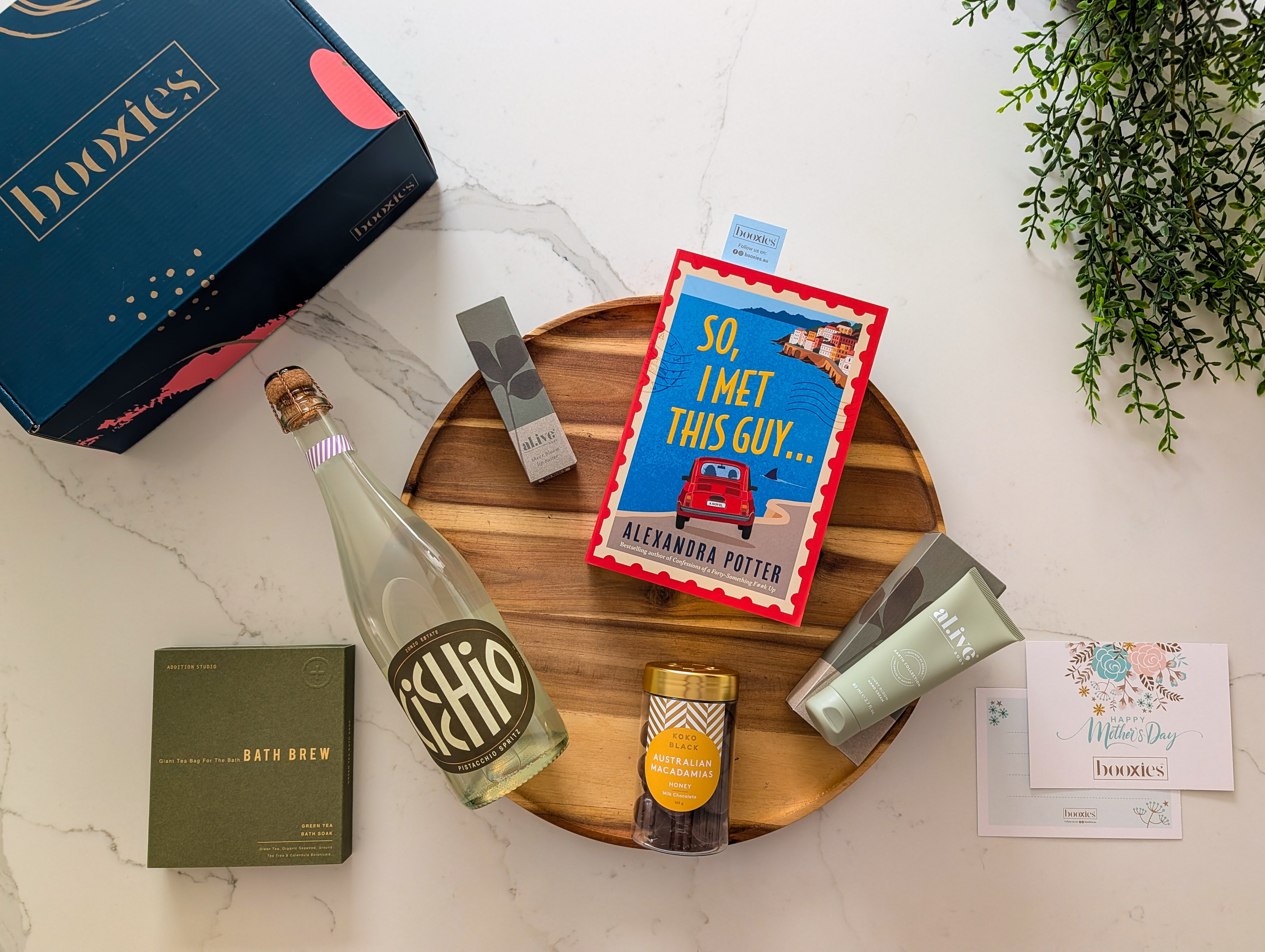 Gourmet gift set with a book, bottle of Cicchio spritz, and other items on a marble surface for mother's day gift box
