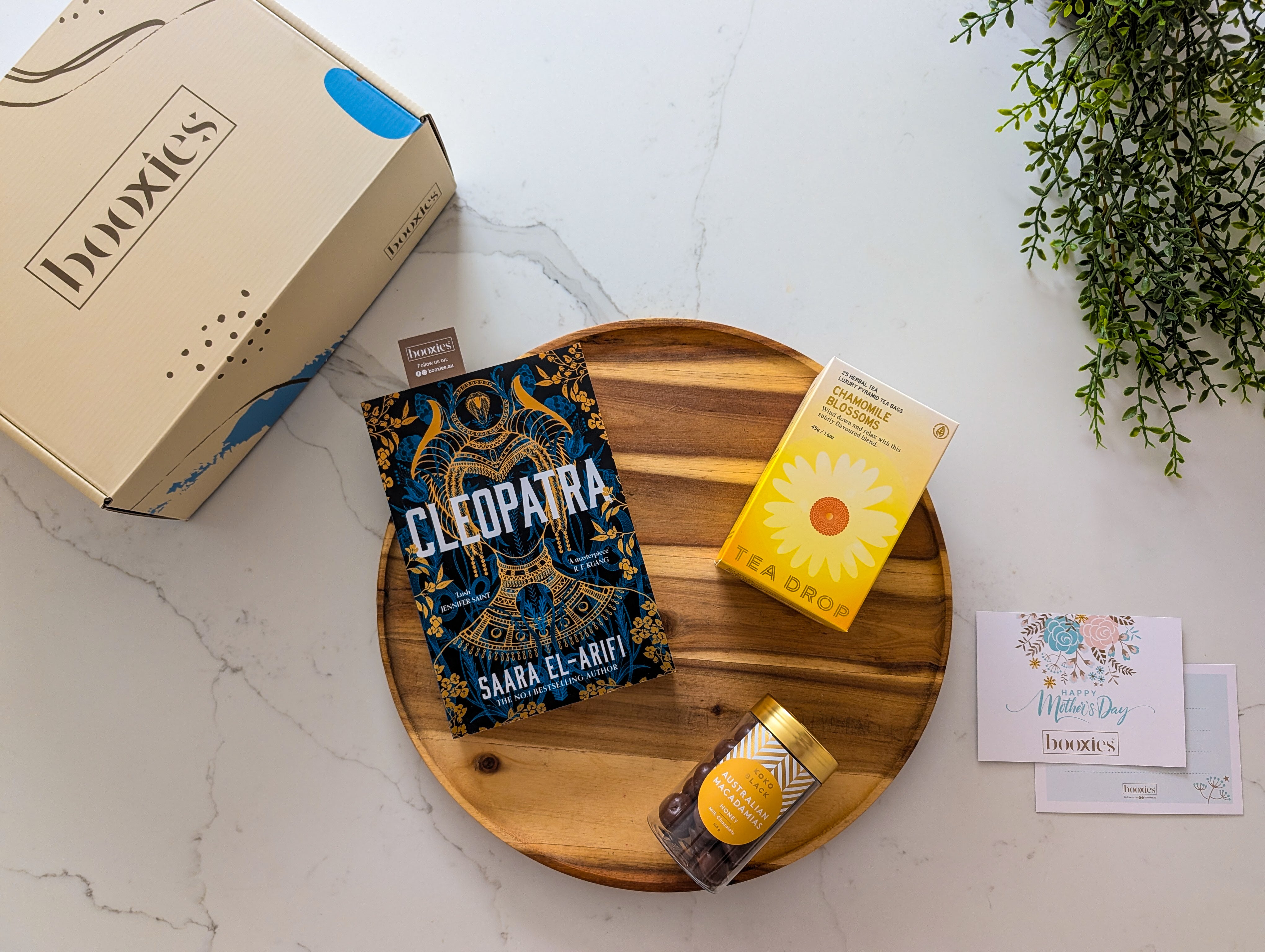 booxies mother's day cosy corner gift box including a book, tea from Teadrop tea and chocolate from koko black on a wodden tray and white marble surface