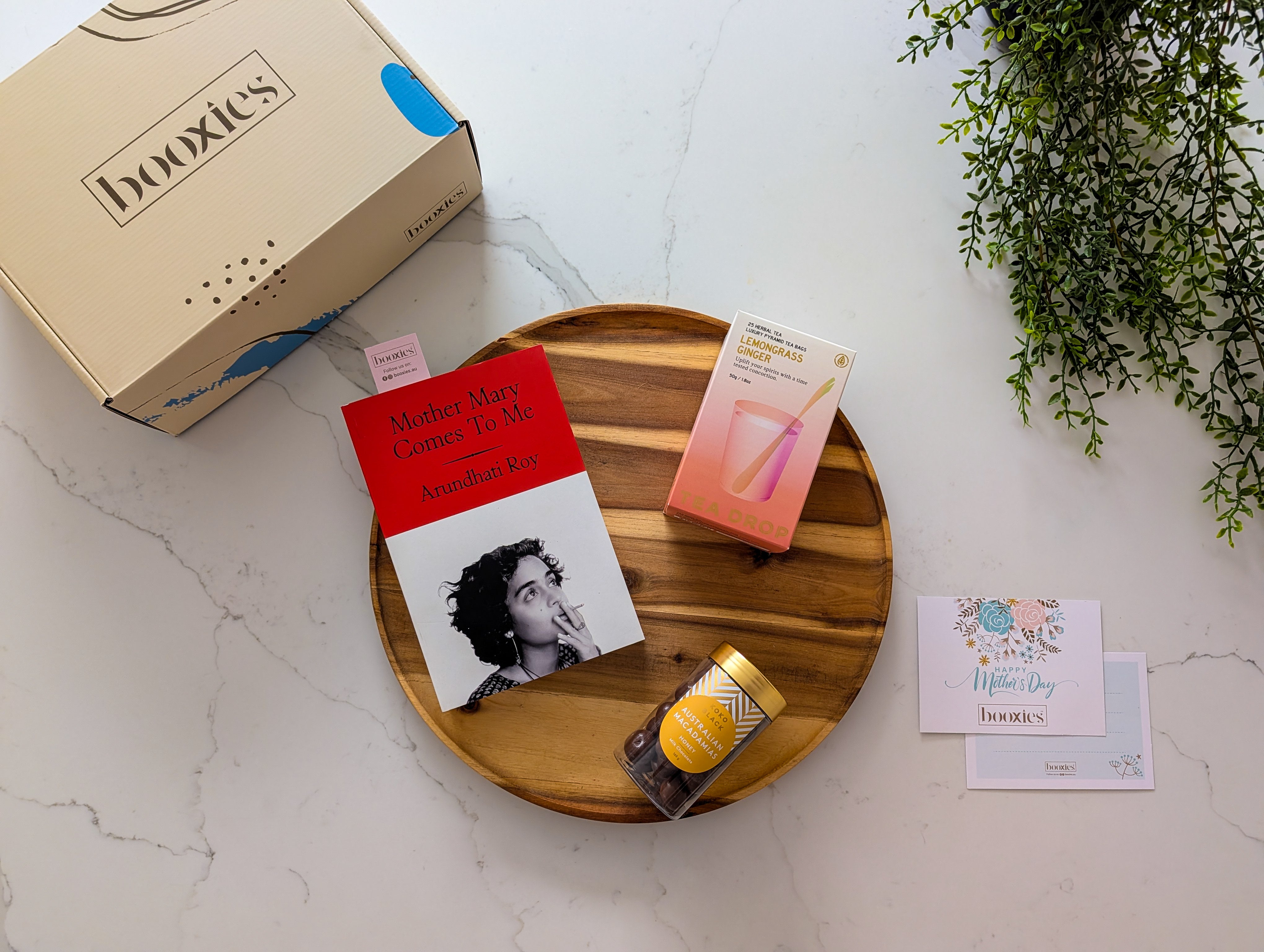 booxies mother's day cosy corner gift box including a book, tea from Teadrop tea and chocolate from koko black on a wodden tray and white marble surface