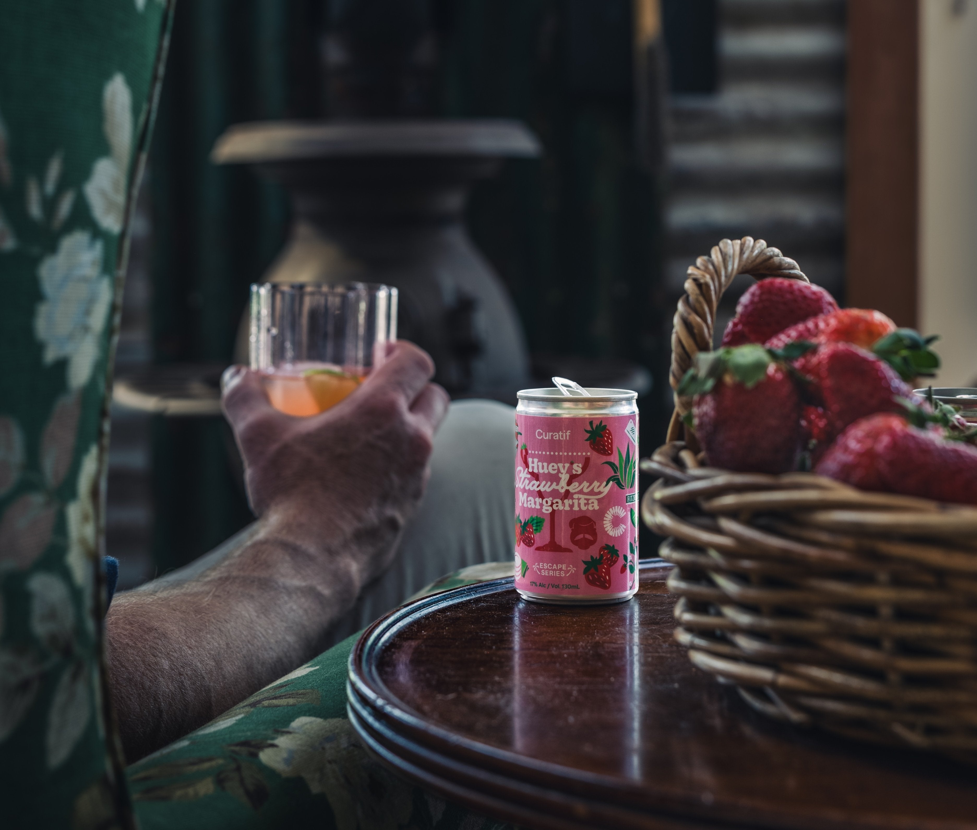 someone's hand holding a strawberry margaritas
