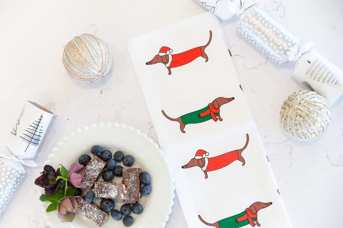 Coasters with Christmas-themed dachshund designs on a white surface with decorative items.